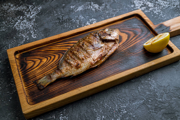Dorado on grill on beautiful wooden board - Φωτογραφία, εικόνα