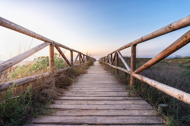 A closeup shot of a long wooden bridge leading to a beach - Fotoğraf, Görsel