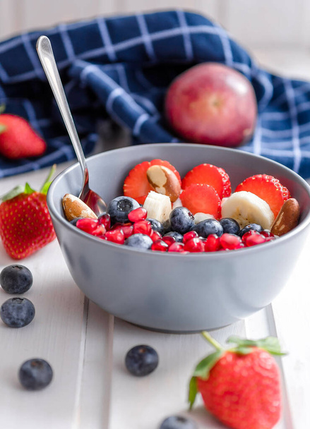 A bowl of fresh berries and fruit on a white table, healthy lifestyle - Valokuva, kuva