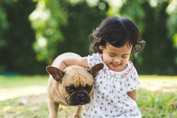 A cute Asian female child and her pet French Bulldog - Foto, Bild