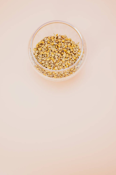 A vertical shot of buckwheat in a glass bowl isolated on a pink background with copy space - Photo, image