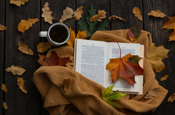 倒れた葉、コーヒー、オープンブックフラットレイ写真。木製の背景に秋の居心地の良い組成。コーヒー、本、葉のカップ。素朴で暖かくてリラックスした朝のコンセプト - 写真・画像