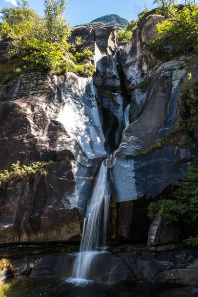 A vertical shot of a waterfall on the rocks in Ticino, Switzerland - Photo, Image