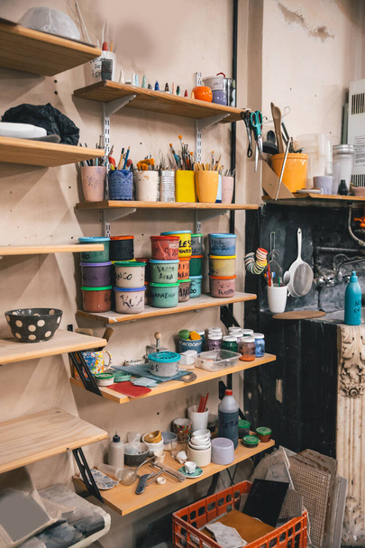 A vertical shot of paints and brushes on shelves in a workshop - 写真・画像