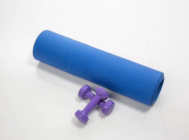 A yoga matt and dumbbells isolated on a white background - Zdjęcie, obraz