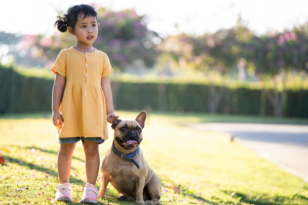 A little Thai girl playing with her lovely french bulldog in the park - Foto, Bild