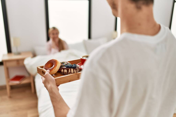 Чоловік дивує свою дівчину сніданком на ліжку вдома
. - Фото, зображення