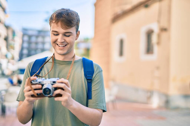 Fiatal kaukázusi turista férfi mosolyog boldog segítségével vintage kamera a városban. - Fotó, kép