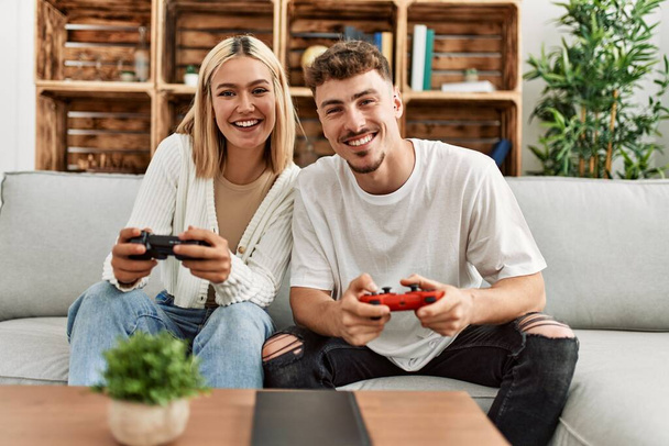 Young caucasian couple smiling happy playing video game at home. - Photo, Image