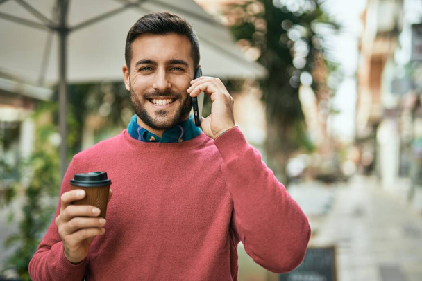 Fiatal spanyol férfi beszél az okostelefonon kávézik a városban.. - Fotó, kép