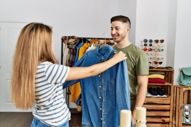 Giovane coppia ispanica sorridente felice scegliendo vestiti al negozio di abbigliamento. - Foto, immagini