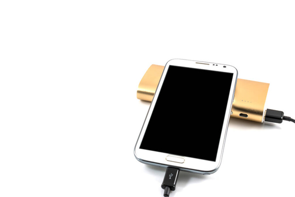 Gold power bank charging white smart phone on white background - 写真・画像