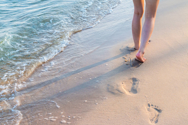 Osamělá dívka kráčející po písku se stopami s vlnou - Fotografie, Obrázek