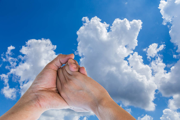Milenec držet ruku na modré obloze s mrakem na slunečný den - Fotografie, Obrázek