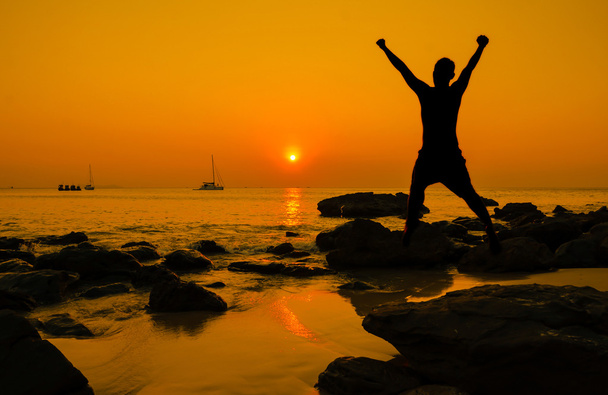 gelukkig sprong tijdens zonsondergang op het strand - Foto, afbeelding