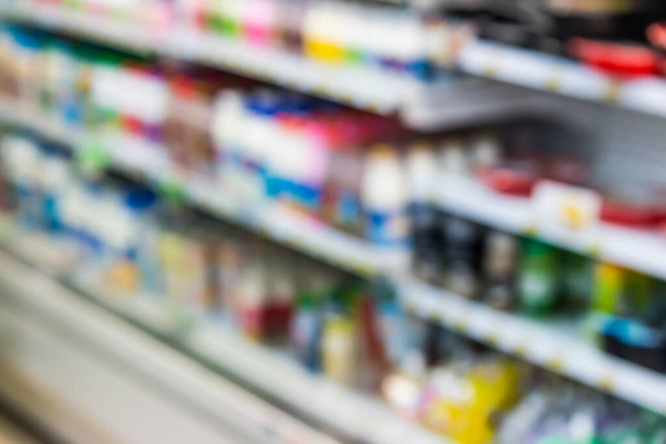 пляшки молочних продуктів на полиці холодильника на фоні супермаркету
 - Фото, зображення