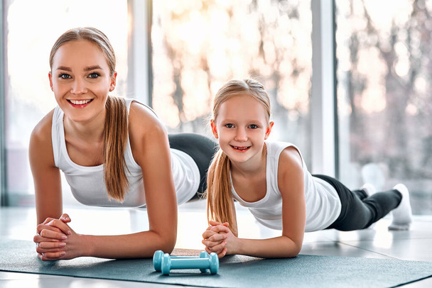 母親と娘が一緒に板運動をしている。健康、家族の概念 - 写真・画像