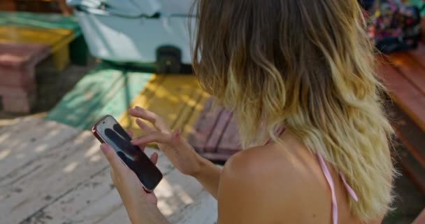blonde girl uses the phone, runs her finger across the screen - Materiał filmowy, wideo