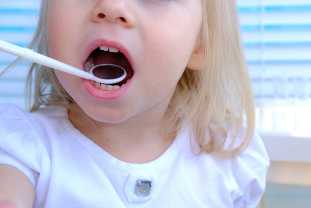 primo piano mani femminili, dentista, medico esamina la cavità orale di un piccolo paziente, ragazza bionda 2 anni, molari crescono, bambino con bocca aperta, primo piano della bocca dei bambini, denti bianchi  - Foto, immagini