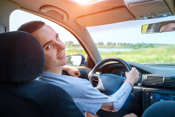 Młody biały mężczyzna z amputowaną ręką prowadzi samochód z protezą - Zdjęcie, obraz
