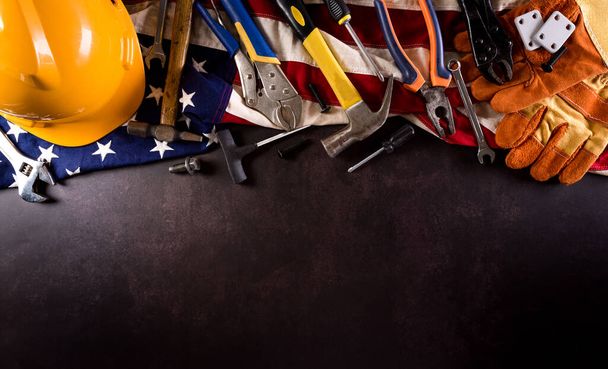 С Днем Труда. Американский флаг с различными строительными инструментами на фоне темного камня. - Фото, изображение