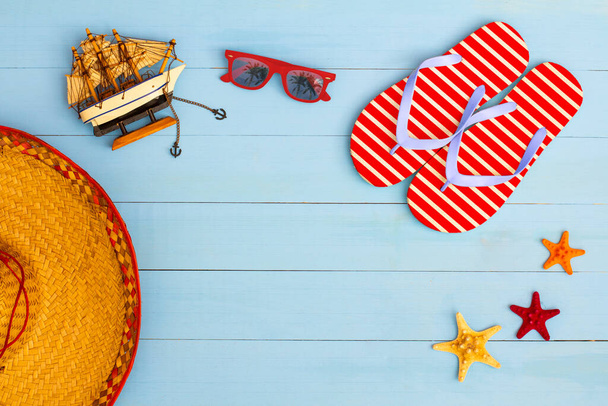 Heure d'été sur une vue fraîche sur la table en bois peint bleu clair avec lunettes de soleil, tongs, voilier, chapeau et étoile de mer - Photo, image