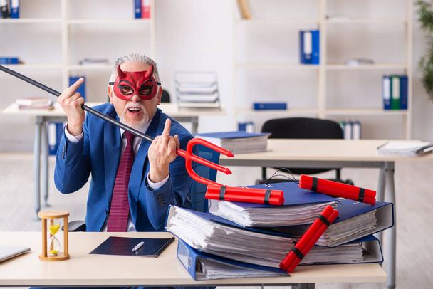 Oude mannelijke duivel werknemer met dynamiet in het kantoor - Foto, afbeelding