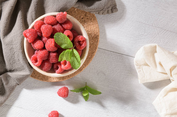 Ripe sweet raspberries in bowl on wooden table. Close up, top view. - Foto, Bild