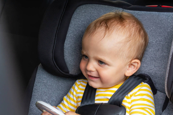 Happy baby boy sitting in car seat.  - Фото, изображение