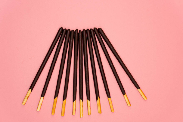A closeup shot of chocolate sticks on a pink background - Foto, Bild