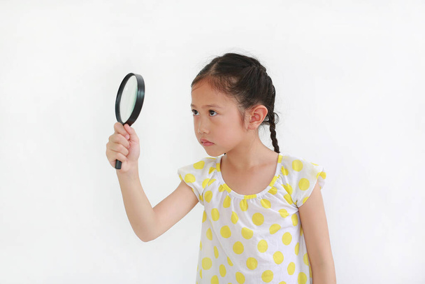 Asian little girl child looking through magnifying glass over white background - 写真・画像