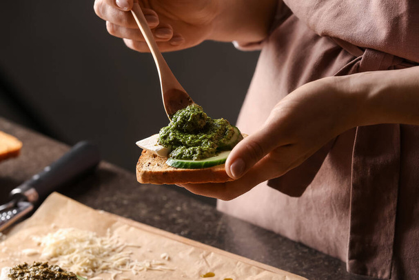 Vrouw maakt lekkere toast met pesto saus, close-up - Foto, afbeelding