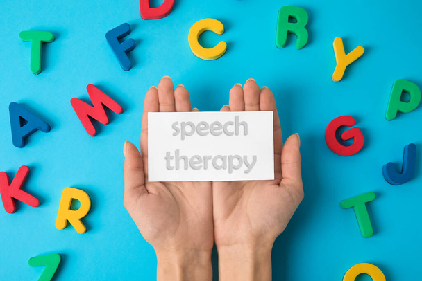 Frau und Papier mit Text SPEECH THERAPY und Buchstaben auf farbigem Hintergrund - Foto, Bild