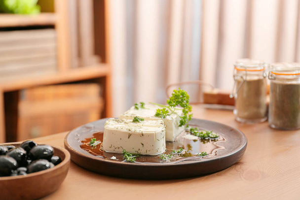 Plate of tasty feta cheese with spices on table in kitchen - Foto, Bild