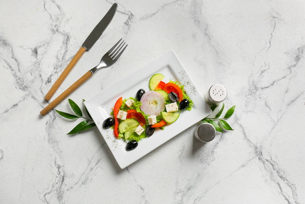 Тарелка с вкусным греческим салатом на светлом фоне - Фото, изображение