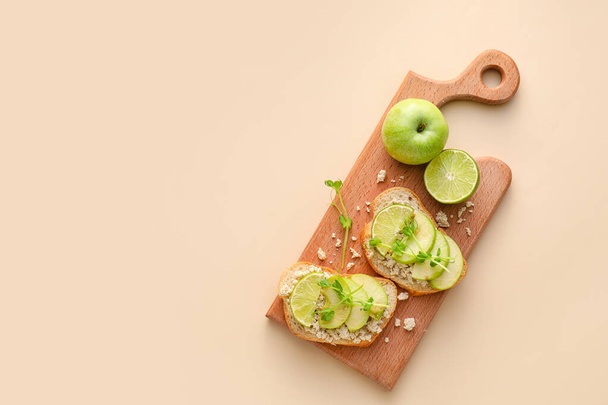 Вкусные брускетты с яблоком, лаймом и хумусом на цветном фоне - Фото, изображение