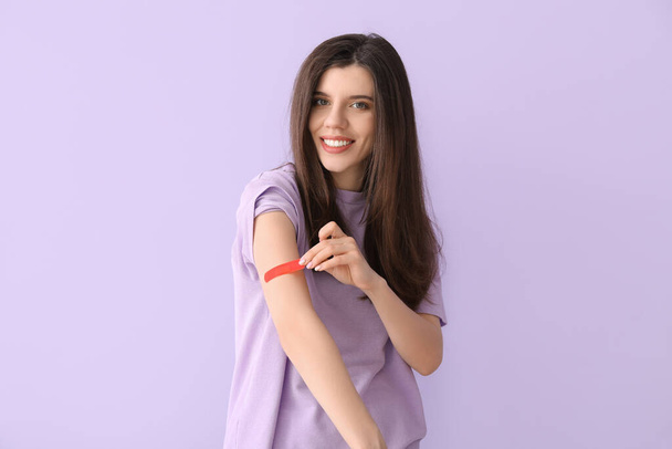 Jonge vrouw verwijderen van medische patch tegen kleur achtergrond - Foto, afbeelding