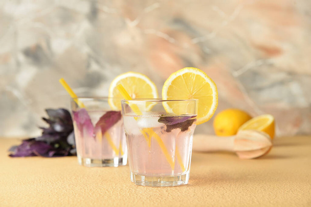 Стаканы вкусного лимонада с базиликом на цветном фоне - Фото, изображение