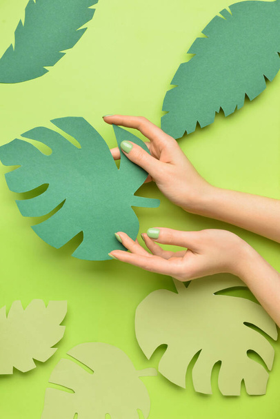 Жіночі руки з листям паперу на кольоровому фоні
 - Фото, зображення