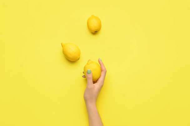 Female hand with lemons on color background - Фото, изображение