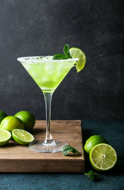 Glass of cold daiquiri cocktail and limes on dark background - 写真・画像