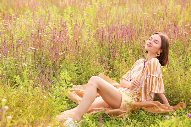 Beautiful young woman relaxing in blooming field - Фото, зображення