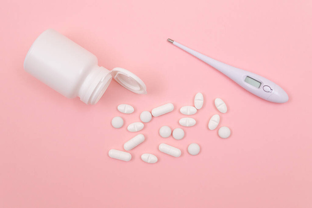 White Pills or Tablets with Electronic Thermometer on Pink Background - Fotografie, Obrázek