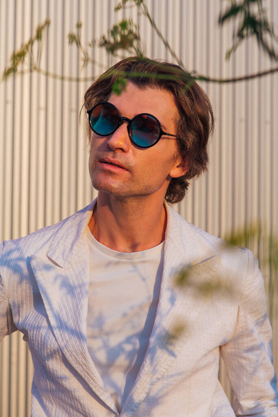 Close up portrait of a handsome man with round hippie sunglasses during sunset - Foto, Bild