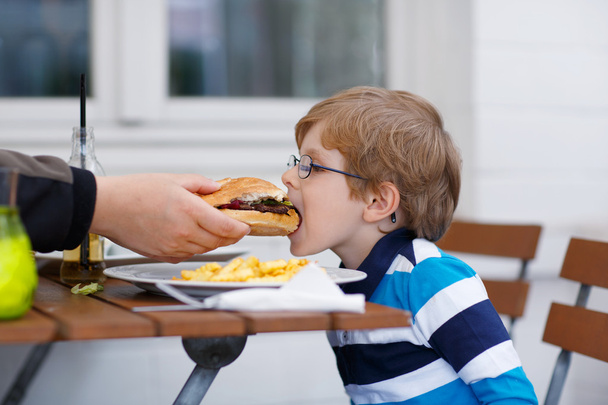 Menino comendo fast food: batatas fritas e hambúrguer
 - Foto, Imagem