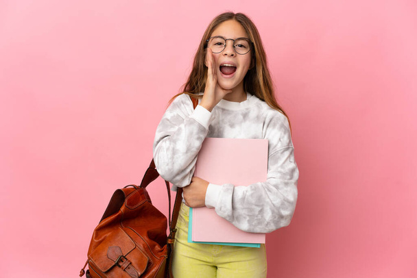Studentin kleines Mädchen über isoliertem rosa Hintergrund schreit mit weit geöffnetem Mund - Foto, Bild