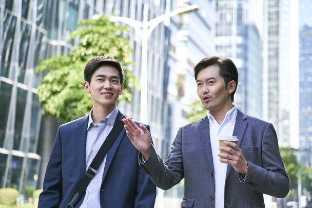twee Aziatische zakenmensen lopen praten op straat in de moderne stad - Foto, afbeelding