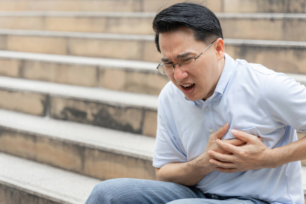 azjatycki mężczyzna cierpiący na silny ból w klatce piersiowej zawał mięśnia sercowego - starsza choroba serca - Zdjęcie, obraz