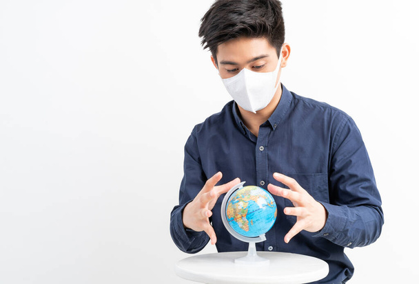 Asian man wearing Face Mask holding map of the globe world map in hand  , Quarantine yourself to protect spread Coronavirus Covid-19 - Photo, Image