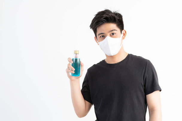 Homem asiático usando máscara facial segurando álcool para lavar as mãos para proteger o Coronavirus covid-19 na sala de quarentena, Quarentena-se para proteger a propagação Covid-19 - Foto, Imagem